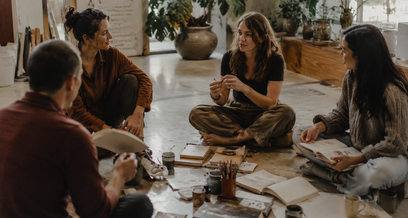 Small group sitting in a circle with journals and art materials, natural light